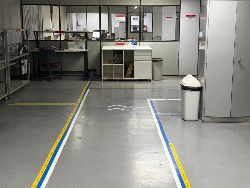 Corredor da fábrica da Ímpeto com faixas no piso e, ao fundo, a área de embalagem