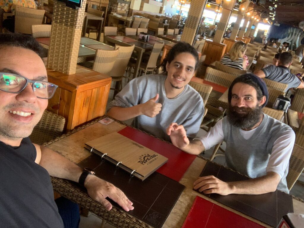 Selfie de três integrantes da equipe sentados à mesa de um restaurante