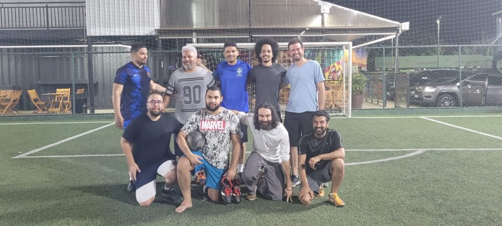 Grupo de amigos posando em um campo de futebol society à noite