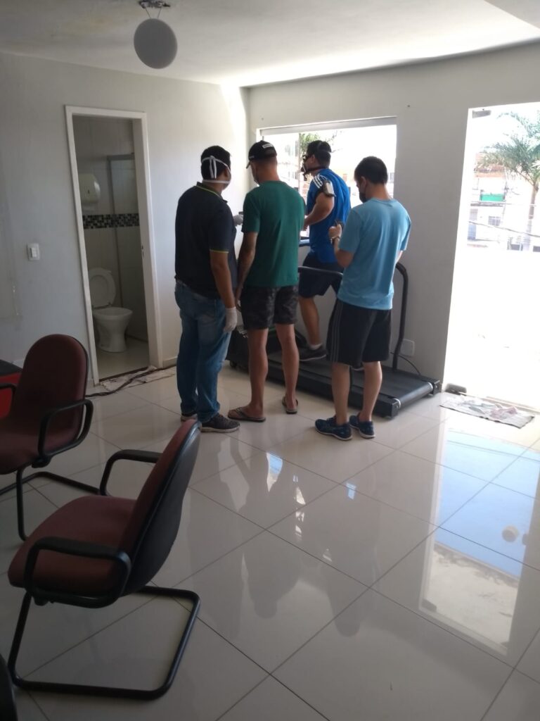 Pessoa correndo na esteira com máscara enquanto outras três acompanham o teste